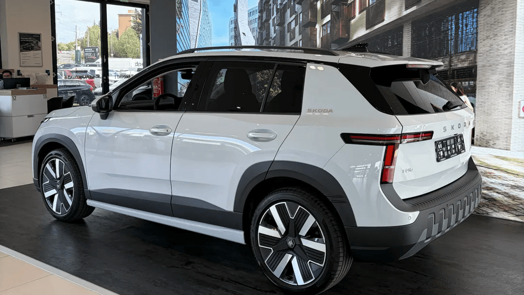 Bílá Škoda Epiq v prodejním salonu, zezadu ze tří čtvrtin, s nápisem SKODA na karoserii